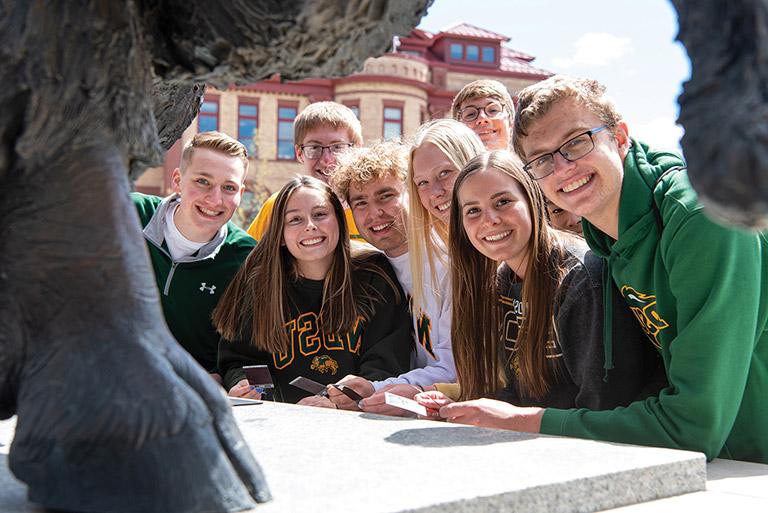 Group of students gathered by NDSU bison statue